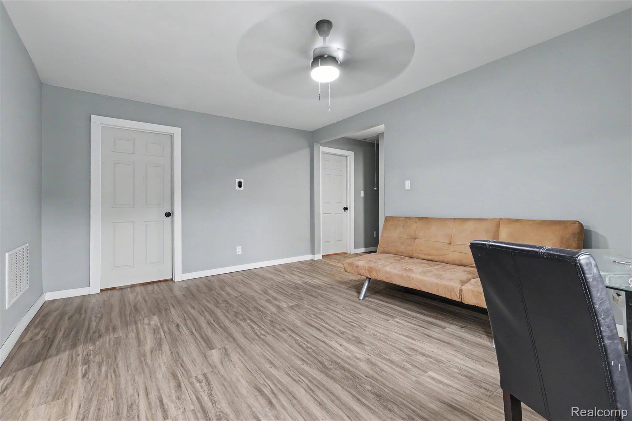 8397 Lane Street Detroit, MI 48209 - Photo 22 of 41 Wood-finish flooring, light blue wall paint, white trim, and a ceiling fan with integrated lighting