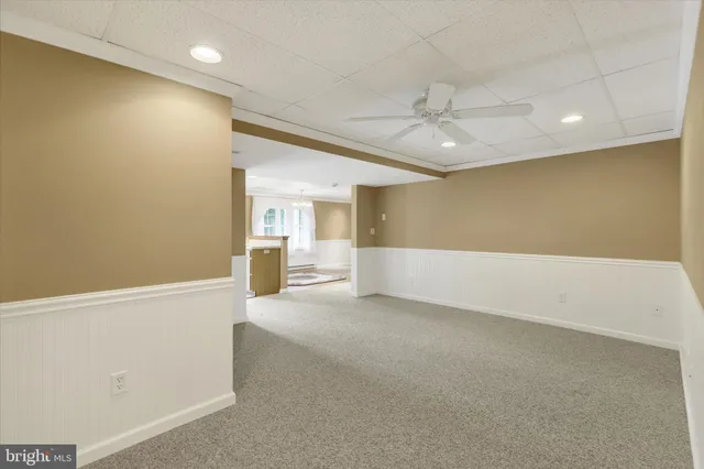 an empty room with chandelier fan and windows