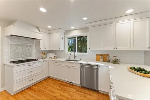 a kitchen with granite countertop white cabinets sink and stainless steel appliances