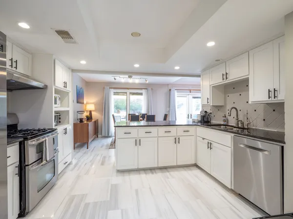a large kitchen with stainless steel appliances granite countertop a lot of counter space and wooden floors