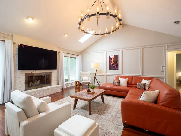 a living room with furniture a flat screen tv and a chandelier