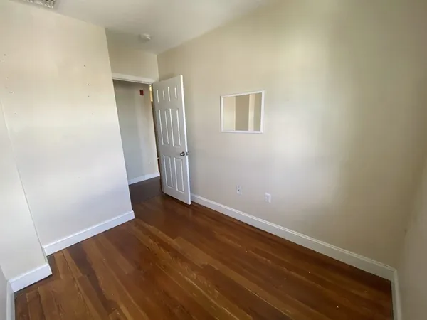 an empty room with wooden floor and entrance