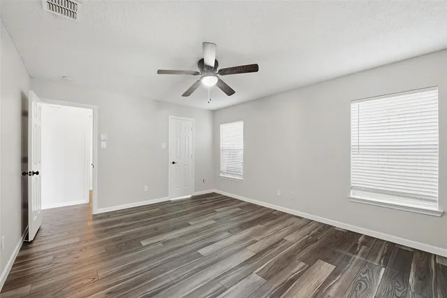 a view of empty room with wooden floor and fan