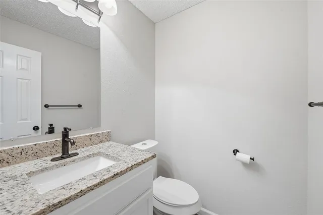 a bathroom with a granite countertop sink a toilet and mirror