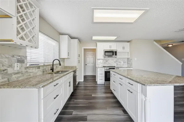 a large kitchen with a granite countertop sink and white cabinets
