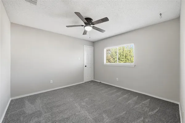 an empty room with window and ceiling fan