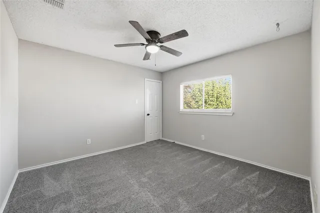 an empty room with window and ceiling fan