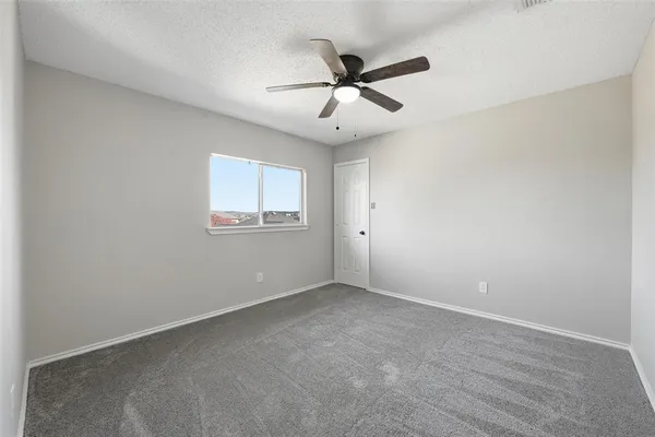 an empty room with a window and a fan
