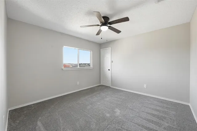 an empty room with a window and a fan