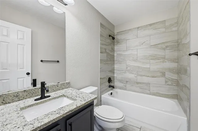 a bathroom with a granite countertop sink a toilet and bathtub