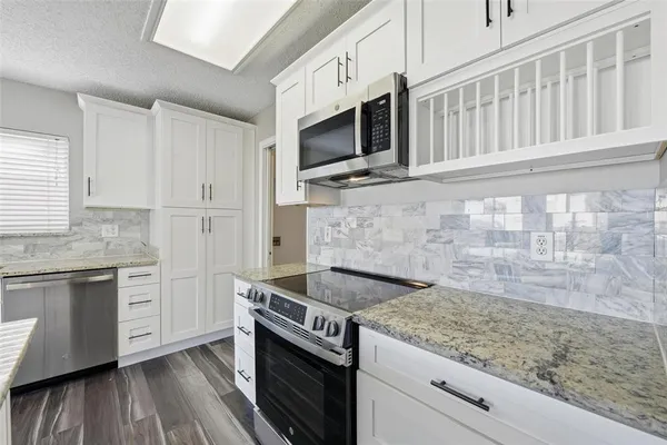 a kitchen with stainless steel appliances granite countertop a stove and a microwave