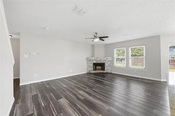 an empty room with wooden floor fireplace and windows