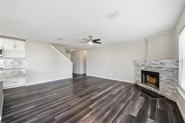 a view of an empty room with wooden floor fireplace and a window