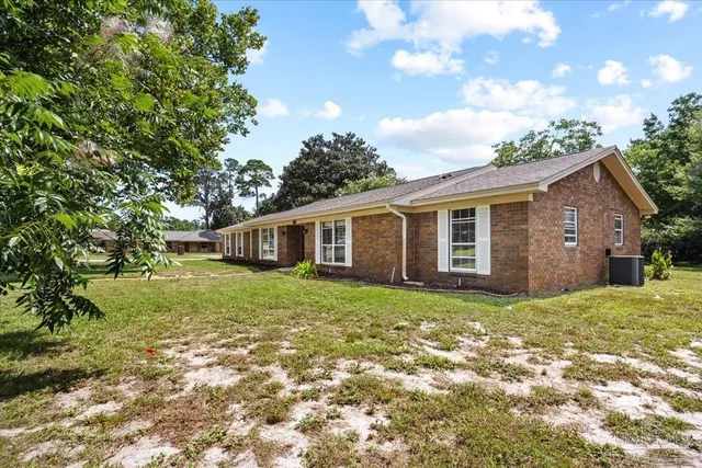 a view of a yard in front of a house with large trees