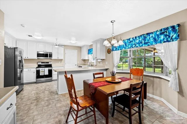 a kitchen with stainless steel appliances granite countertop a stove a refrigerator a kitchen island a dining table and chairs