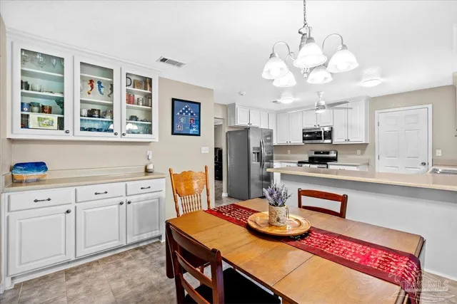 a kitchen with stainless steel appliances kitchen island granite countertop a sink a refrigerator and white cabinets