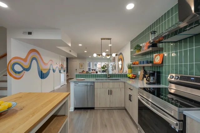 a kitchen with stainless steel appliances granite countertop a sink dishwasher and a dining table with wooden floor