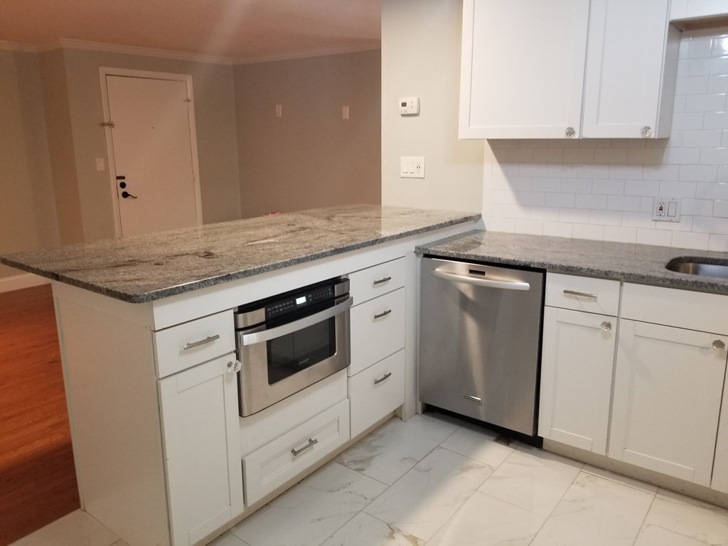 24-26 Inman Street, Unit 28 Lawrence, MA 01843 - Photo 8 of 13 a kitchen with white cabinets and white appliances