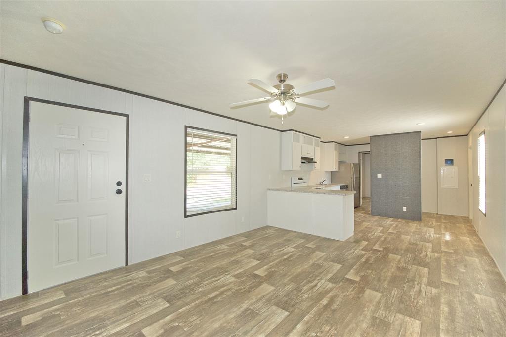 60 Tecumseh Road Valley View, TX 76272 - Photo 7 of 20 Open-concept living area featuring wood-finish flooring, a contemporary ceiling fan, and ample natural light from a prominent window