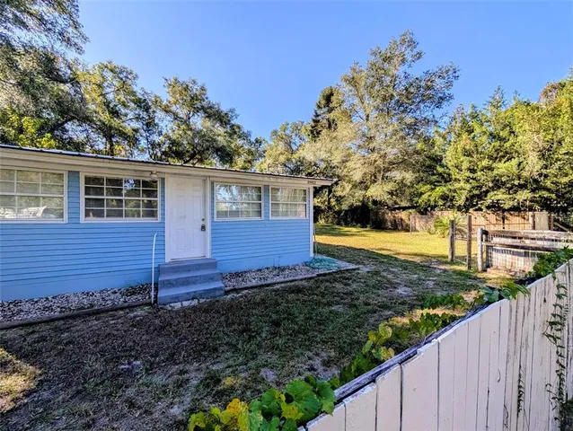 a view of a house with backyard and trees