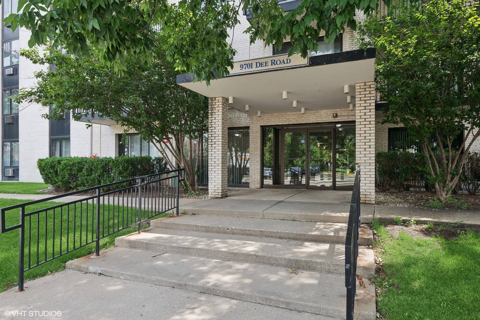 9701 North Dee Road, Unit 2I Niles, IL 60714 - Photo 2 of 24 a view of a white house with a small yard and potted plants