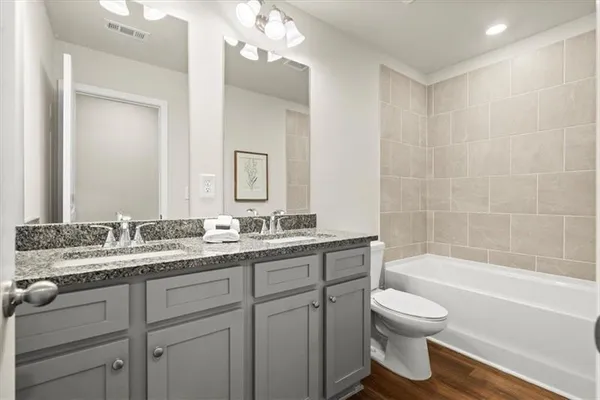 a bathroom with a granite countertop sink a toilet mirror and bathtub
