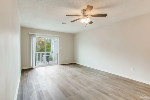 an empty room with wooden floor fan and windows