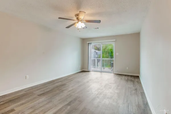 an empty room with wooden floor fan and windows