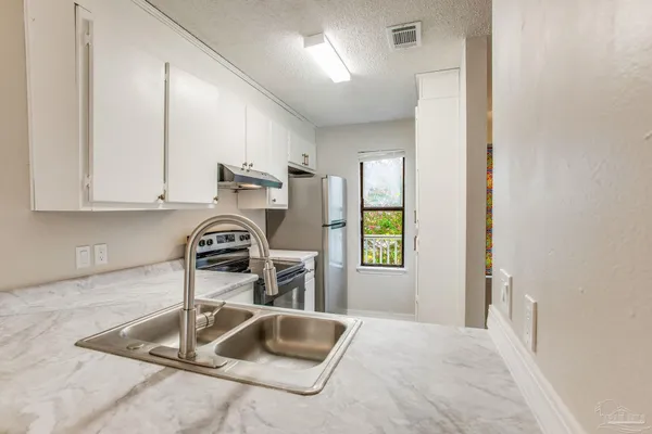 a kitchen with granite countertop a sink a stove and a wooden cabinets