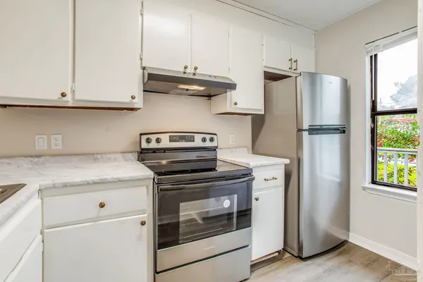 a kitchen with stainless steel appliances granite countertop white cabinets and a stove