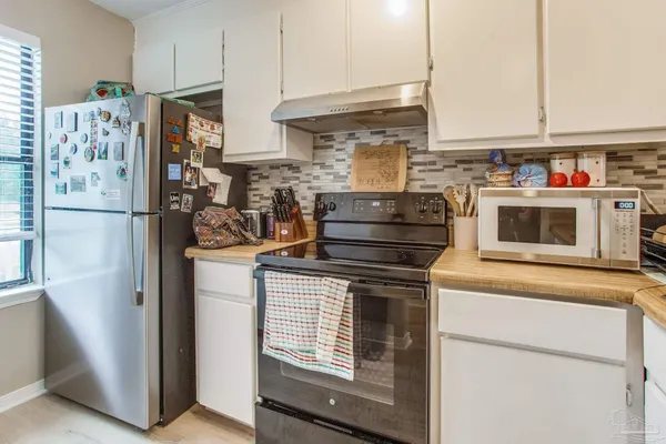a kitchen with stainless steel appliances granite countertop a refrigerator stove and white cabinets