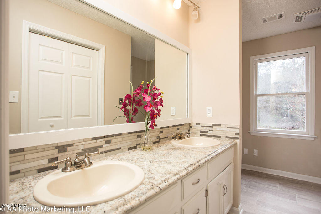 922 Woolfolk Road Fort Valley, GA 31030 - Photo 28 of 38 a bathroom with a granite countertop sink a mirror and a window