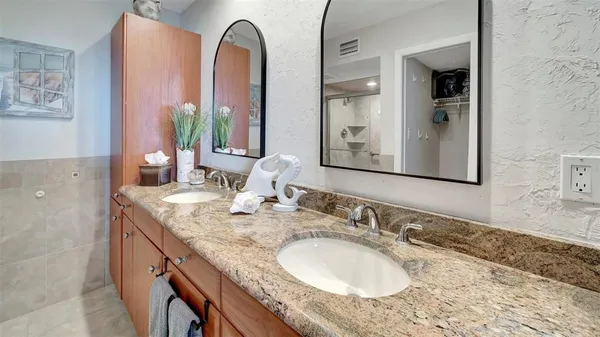 a bathroom with a granite countertop double vanity sink and a mirror