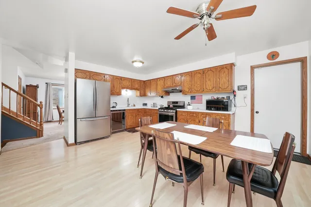 a kitchen with stainless steel appliances a dining table chairs refrigerator and sink