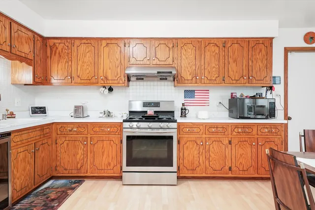 a kitchen with stainless steel appliances granite countertop a stove a sink dishwasher and a refrigerator with wooden cabinets