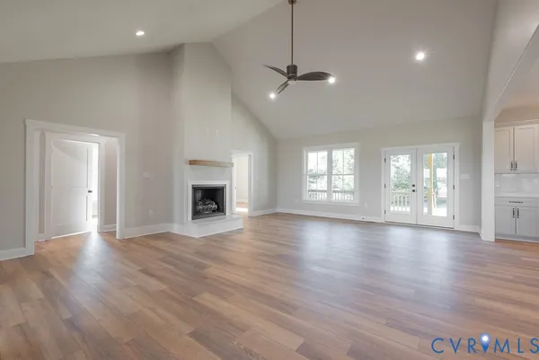 an empty room with wooden floor fireplace and windows