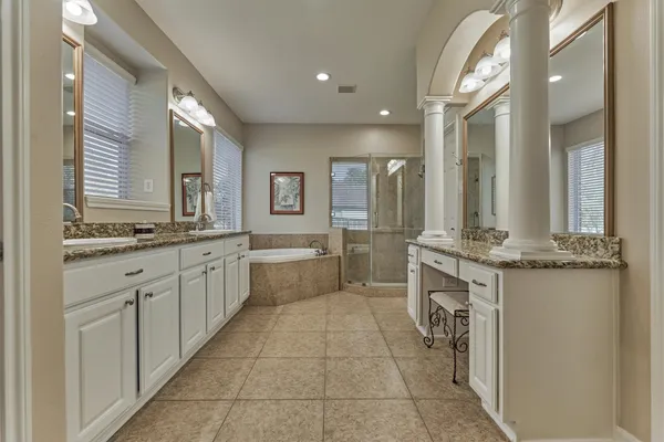 a bathroom with a granite countertop double vanity sink a mirror and a bathtub