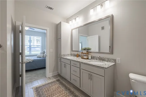 a en suite bathroom with a granite countertop sink a toilet and a mirror