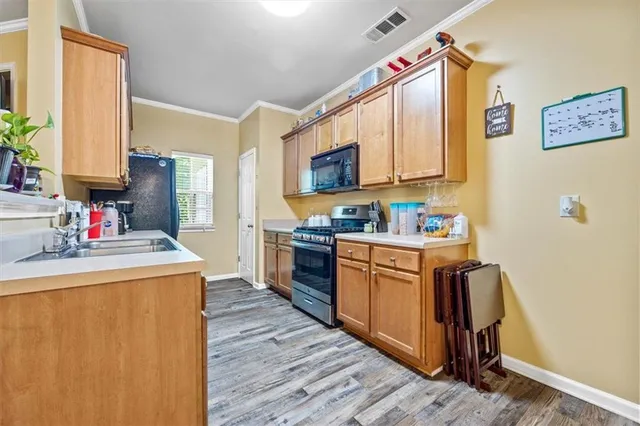 a kitchen with stainless steel appliances granite countertop a stove a sink dishwasher and a refrigerator with wooden floor