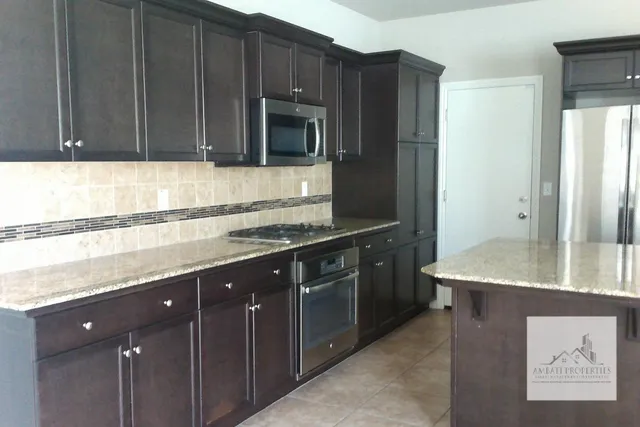 a kitchen with stainless steel appliances granite countertop wooden cabinets a refrigerator and a sink