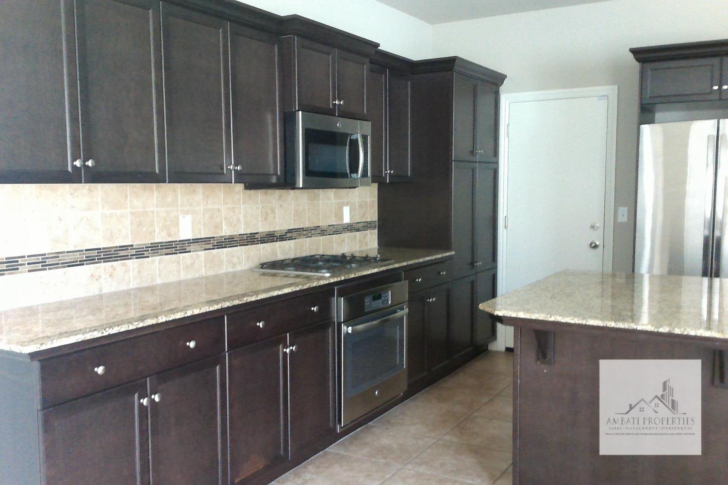 3539 Luminary Way Clovis, CA 93619 - Photo 2 of 13 a kitchen with stainless steel appliances granite countertop wooden cabinets a refrigerator and a sink