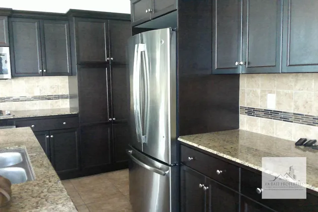 a kitchen with granite countertop a refrigerator and a sink
