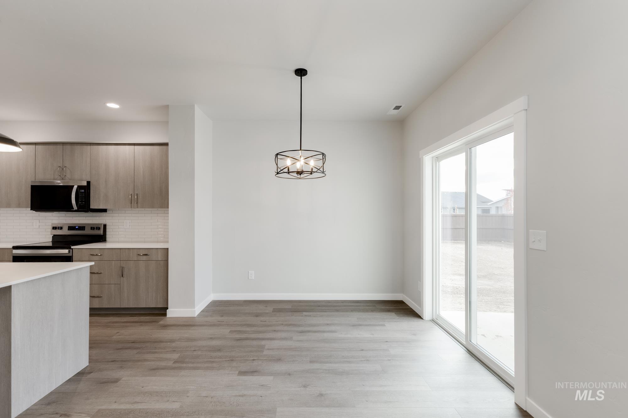903 North Mirror Creek Way Meridian, ID 83642 - Photo 6 of 24 Kitchen featuring a chandelier, stainless steel appliances, hanging light fixtures, decorative backsplash, and modern cabinets