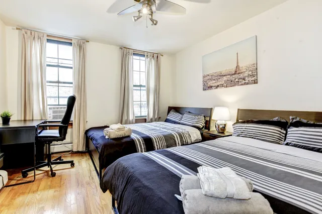 a bedroom with two beds and a desk