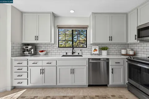 a kitchen with cabinets appliances a sink and a window