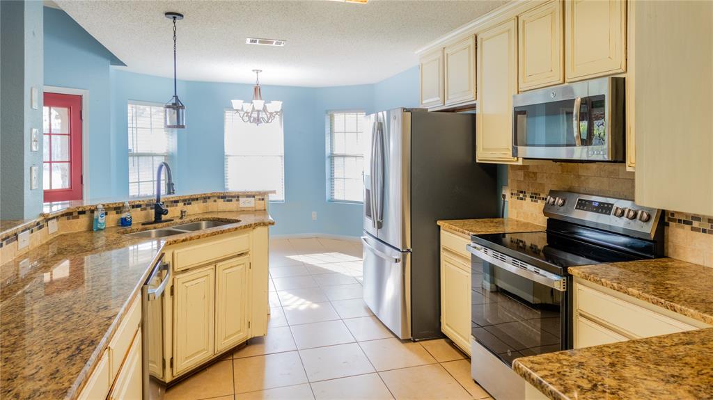 124 Topaz Circle Hewitt, TX 76643 - Photo 9 of 29 Kitchen with stainless steel appliances, decorative backsplash, light stone counters, a chandelier, and a textured ceiling