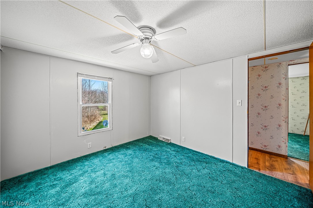 3471 Fox Road Kingsville, OH 44048 - Photo 24 of 50 Spare room featuring a textured ceiling, ceiling fan, and dark colored carpet