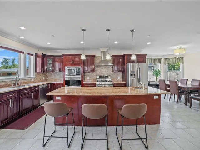 a kitchen with stainless steel appliances granite countertop a refrigerator and a stove top oven