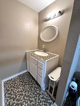 a bathroom with a granite countertop toilet a sink and a mirror
