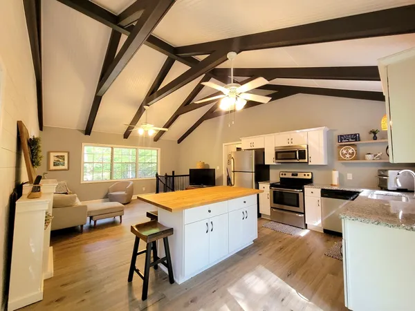 a large white kitchen with a stove a sink dishwasher and a microwave oven with wooden floor